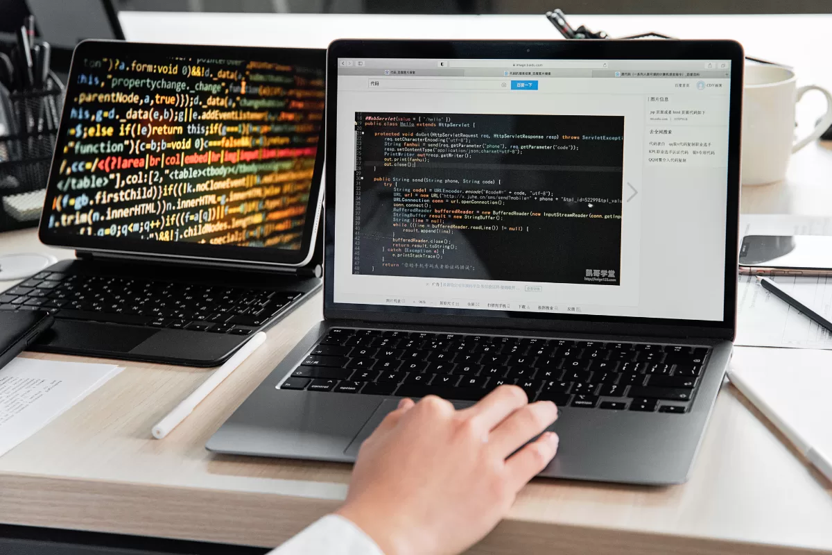 Imagem de dois notebooks com a tela mostrando códigos de programação 