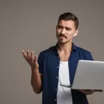 Imagem de um homem confuso segurando um notebook devido a testes flakey