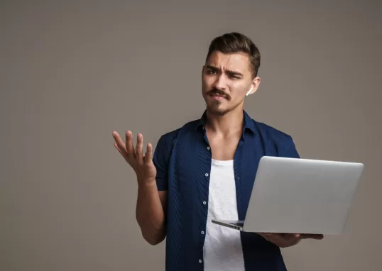 Imagem de um homem confuso segurando um notebook devido a testes flakey