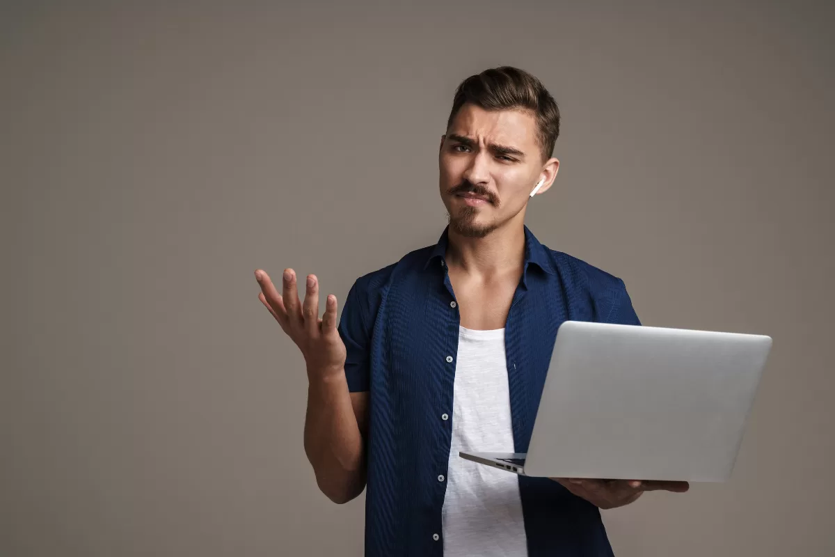 Imagem de um homem confuso segurando um notebook devido a testes flakey