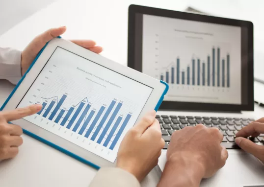 Um tablet e uma tela de computador mostrando gráficos representando lucro