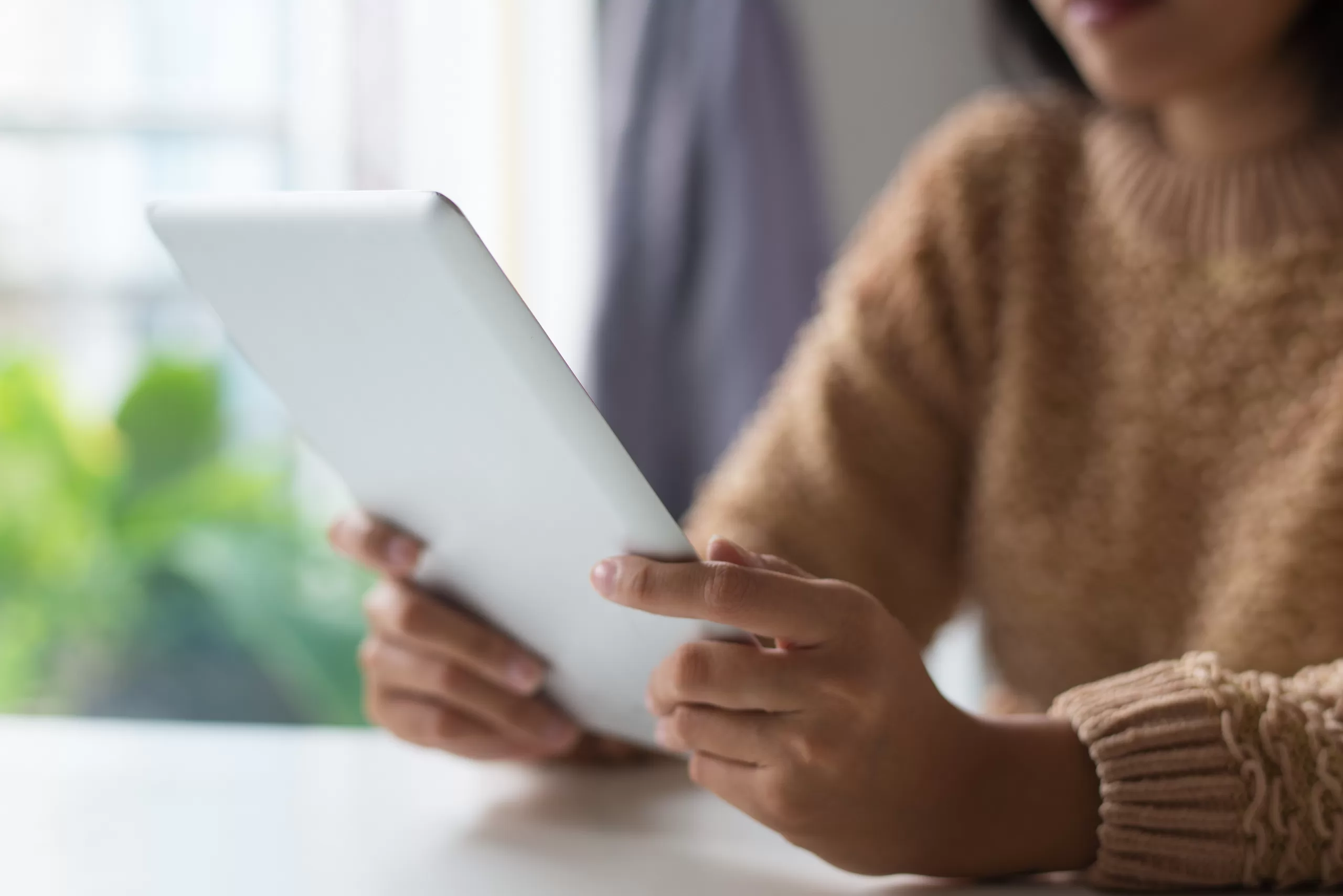 Close-up of a woman using a digital tablet, representing modern digital interaction and technology adoption.