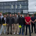 TestBooster team standing in front of the Kärcher headquarters building in Germany, posing for a photo with the company logo and flags visible in the background.