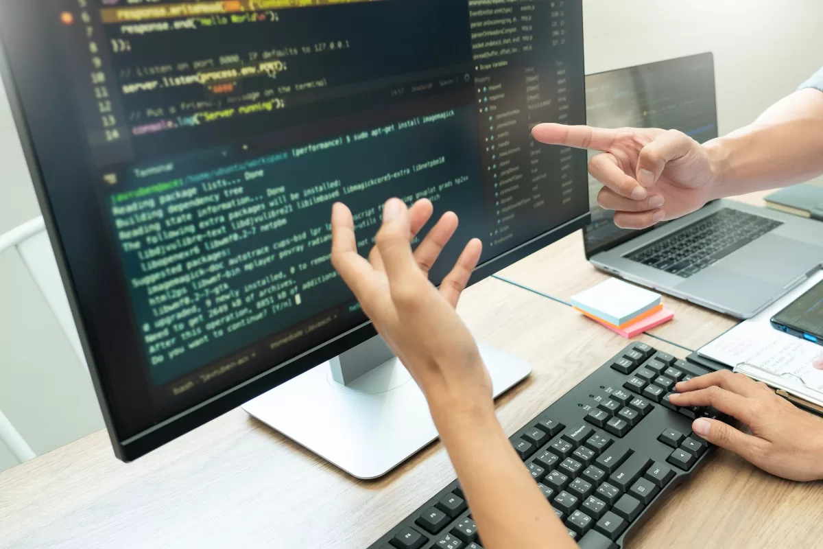 Hands gesturing and a finger pointing at a screen with code and a terminal.