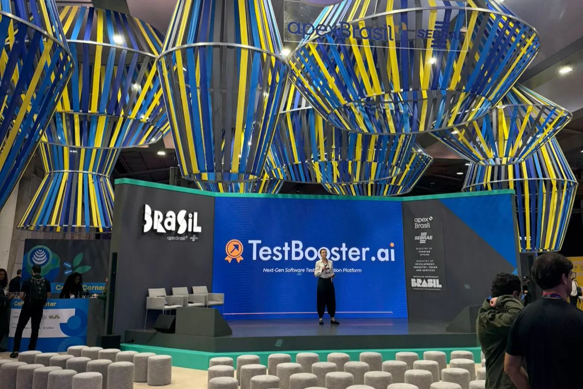 Brazil stage at Web Summit Lisbon featuring TestBooster.ai presentation, decoration with Brazilian flag colored ribbons and audience seated on ottomans