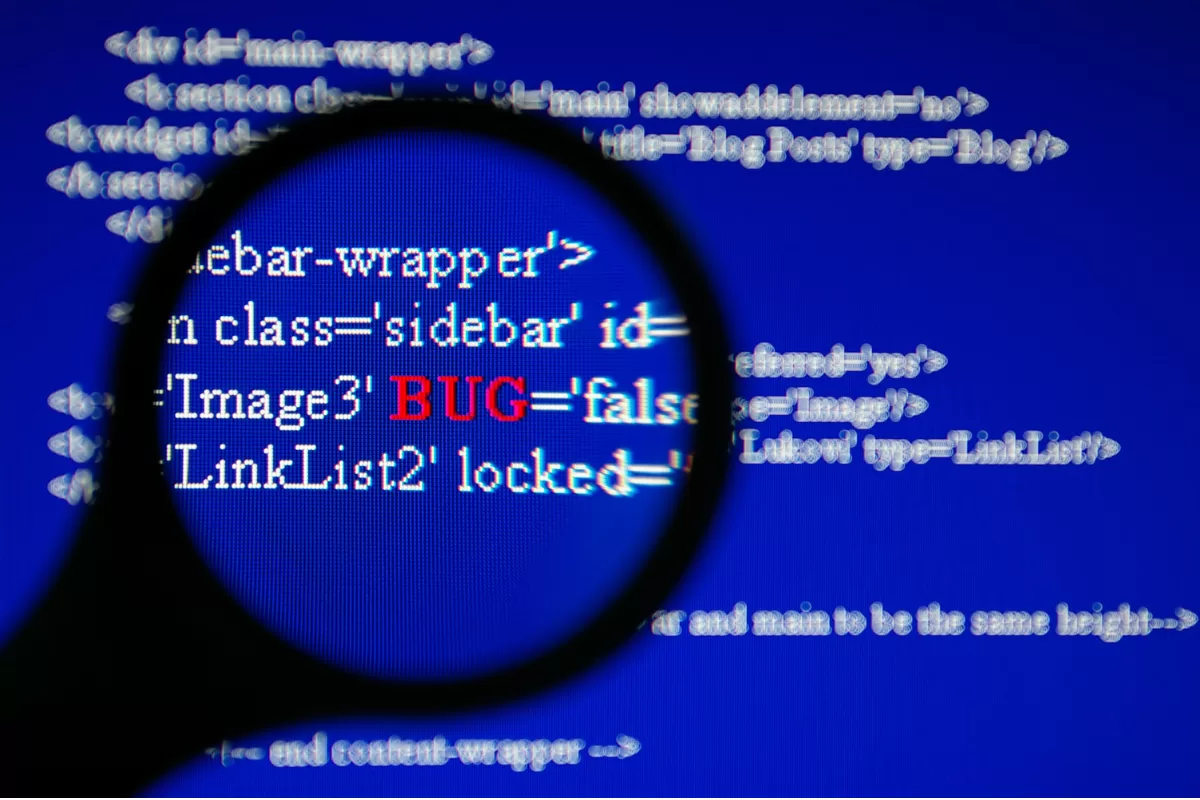 Magnifying glass zooming in on HTML code on blue screen with the word 'BUG' highlighted in red, representing error identification in code
