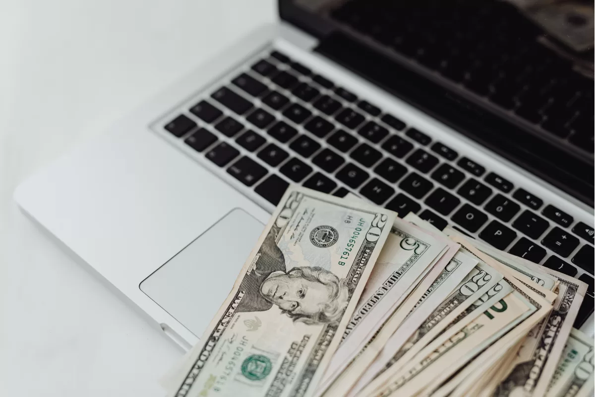 Dollar bills on laptop representing financial transactions and online payments