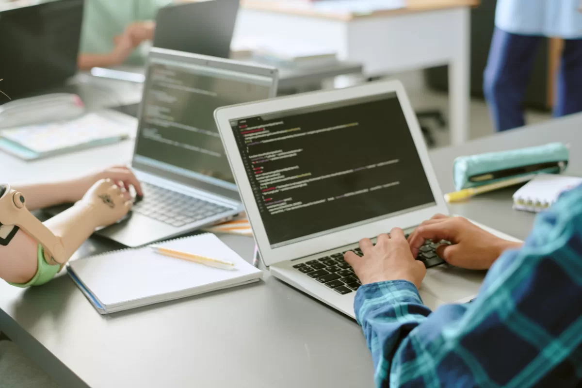 Desenvolvedora trabalhando em laptop com código na tela, realizando testes de software em ambiente colaborativo