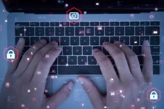 Mãos digitando em teclado de laptop com overlay de ícones digitais representando testes de segurança e automação de software, ilustrando o conceito de testes funcionais automatizados