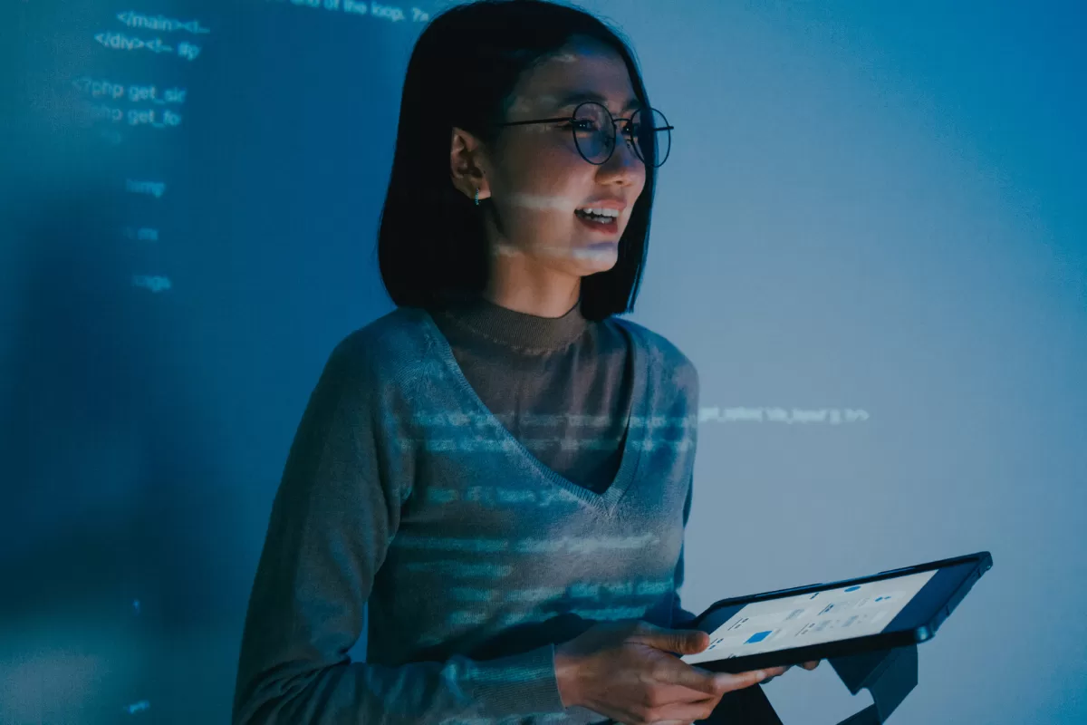 Profissional de QA analisando dashboard com métricas de performance em tablet, monitorando resultados de testes automatizados