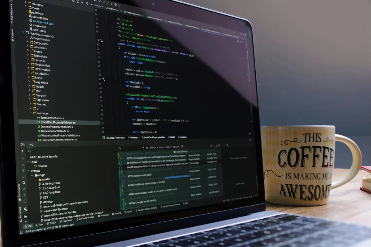 A laptop on a wooden desk next to a mug that reads "This coffee is making me awesome," representing a developer's or QA analyst's workspace.